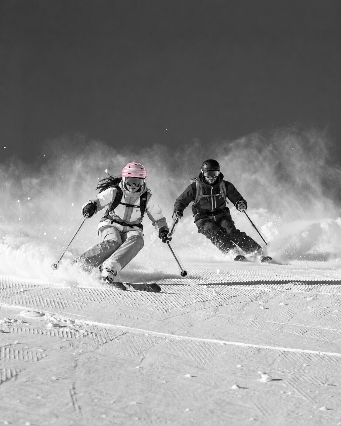 Two skiers carving through fresh snow